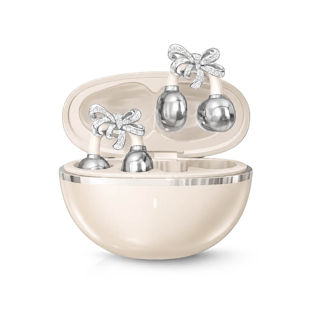 Four silver bell-shaped facial rollers with diamond-encrusted bows, resting in a cream-colored case against a white background.