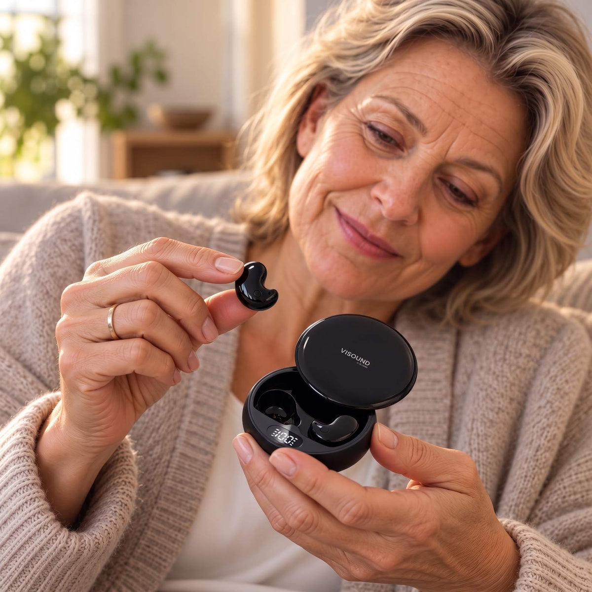 Hand holding a glossy black ViSound Drift earbud above its open case