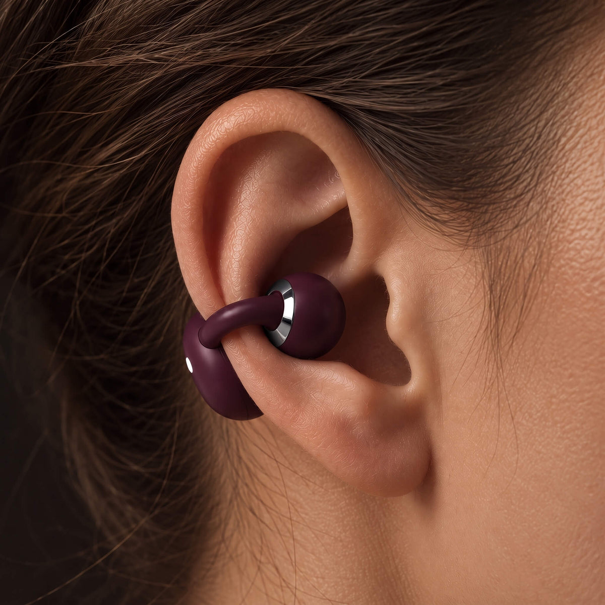 Close-up of a burgundy ViSound Ease clipped on the outer edge of an ear, the ear canal left open