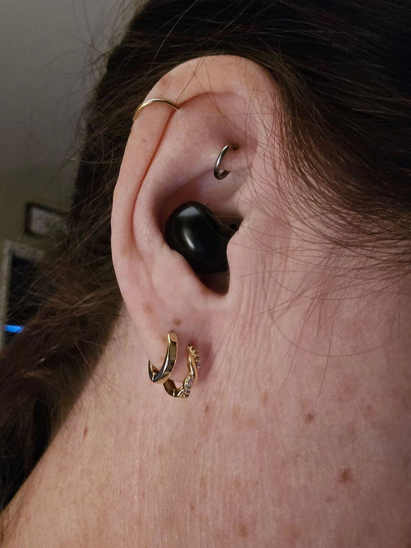 Black ViSound Air earbud worn next to a gold hoop earring